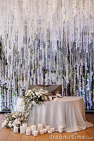 The presidium of the newlyweds in the banquet hall of the restaurant is decorated with candles and green plants Stock Photo