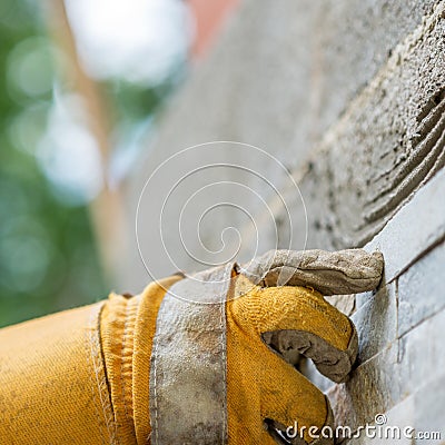 Pressing an ornamental tile into a glue on a wall Stock Photo