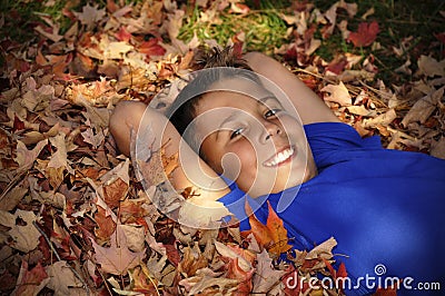 Preteen boy laying in autumn leaves Stock Photo