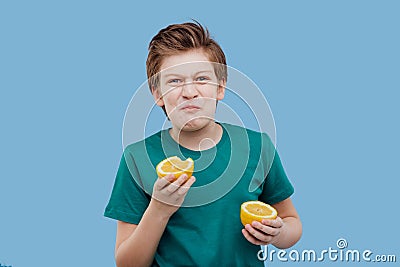 Preteen boy taste a fresh lemon, sour taste Stock Photo
