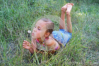 Preteen girl blowing on dandelion Stock Photo