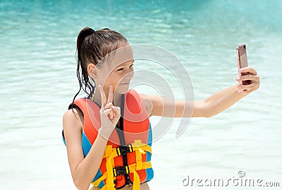 Preteen girl in life vest takes selfie by cell phone camera Stock Photo