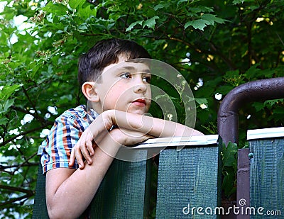 Preteen handsome boy climb village fence Stock Photo