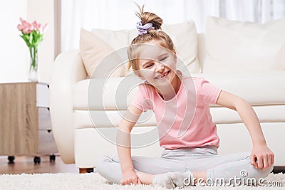 Preteen kid sitting in yoga pose in room Stock Photo