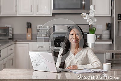 A smiling woman works from her home office in her kitchen Stock Photo