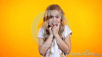 Pretty anxious blond girl biting finger and looking to camera, suffering fear Stock Photo