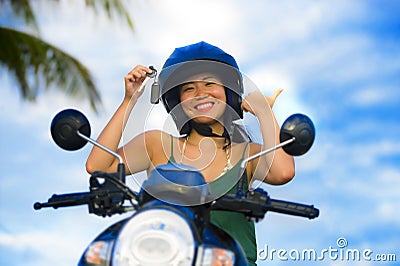 Pretty Asian Chinese girl showing key of new motorbike wearing motorcycle safety helmet smiling proud in scooter buying and rental Stock Photo