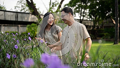 A pretty Asian daughter and her dad are enjoying talking while strolling in their courtyard garden Stock Photo