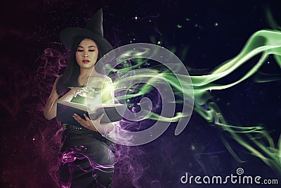 Pretty asian witch woman reading the incantation in book Stock Photo