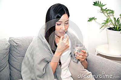 Asian young woman wrapped in a blanket and during illness and taking antipyretics. Stock Photo