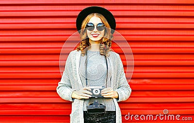 Pretty autumn happy girl holds retro camera on red background Stock Photo