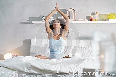 Young African American Woman Doing Yoga In Bed After Sleep Stock Photo