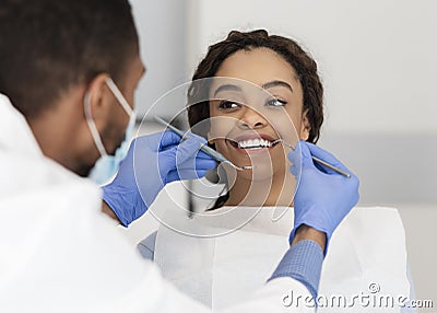 Pretty black lady looking at her dentist with smile Stock Photo