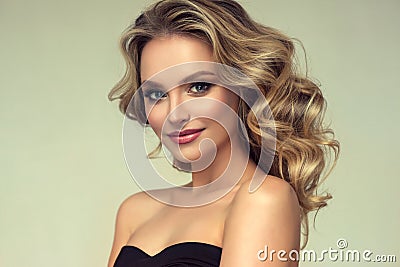 Pretty blond-haired model with curly, loose hairstyle and attractive makeup. Stock Photo