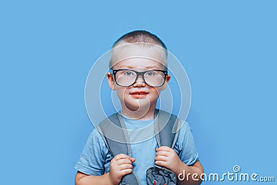 Pretty blonde boy on blue background with backpack unhappy, sad, child don`t want go to school. back to school Stock Photo