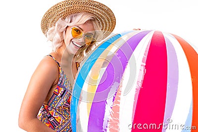 Pretty blonde caucasian female stands in swimsuit with big rubber beach colourful ball and smiles isolated on white Stock Photo