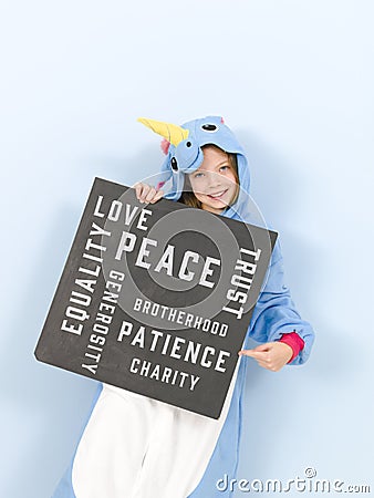 Pretty blonde girl with cozy blue unicorn costume with blackboard with different words on it like love and peace and some more Stock Photo