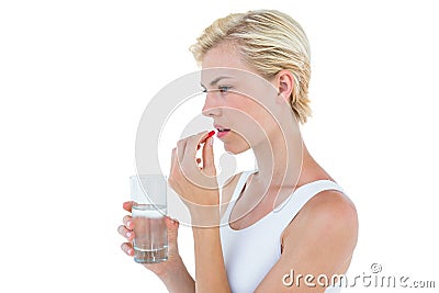 Pretty blonde woman holding glass of water and ready to swallow red pill Stock Photo