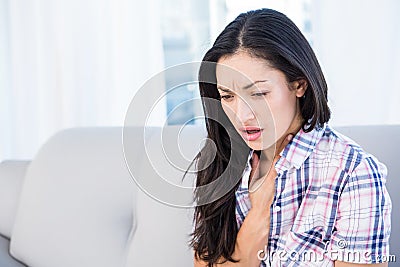 Pretty brunette coughing on couch Stock Photo