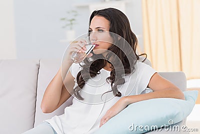 Pretty brunette drinking water on couch Stock Photo