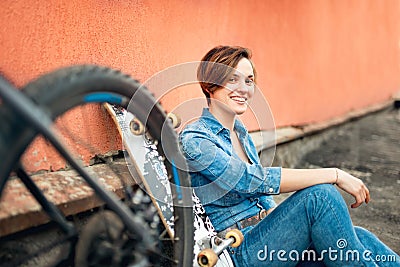 Pretty brunette girl, skater, trendy lifestyle and hipster girl standing with bike and longboard. Stock Photo