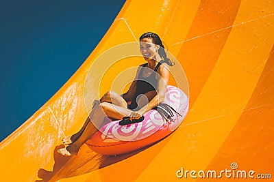 Brunette woman having fun on the water slide in aqua park Stock Photo