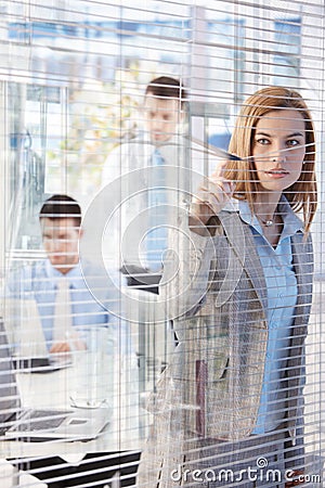 Pretty businesswoman peeping through blind Stock Photo