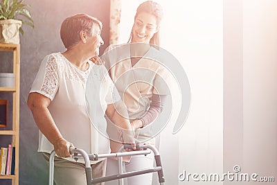 Pretty caregiver and old lady with walker at nursing home Stock Photo