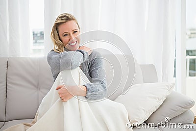 Pretty casual woman sitting on couch under a blanket Stock Photo