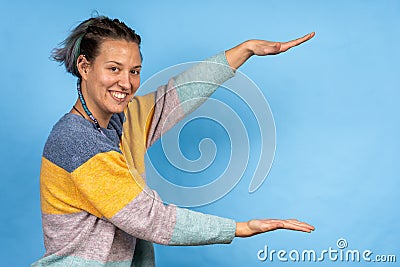 Pretty Caucasian holding something and posing on a blue background - copy space Stock Photo