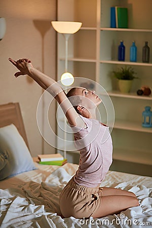 Slim caucasian woman yogi sits on bed stretching after yoga exercise Stock Photo