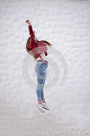 Pretty curvy girl jumping sideways next to a peculiar white wall Stock Photo