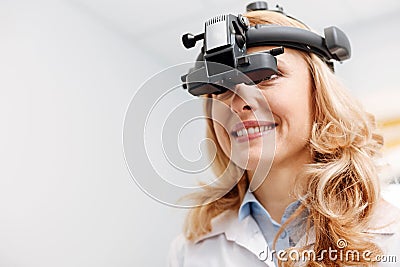 Pretty dedicated prominent specialist wearing ophthalmoscope Stock Photo