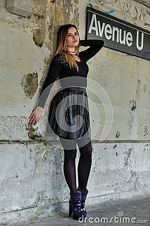 Pretty elegant young woman in black top and skirt posing over grunge wall Editorial Stock Photo