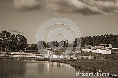 Pretty farm with fences, livestock sheds and lake Stock Photo