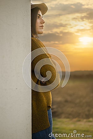Pretty farm girl watching sunset after working in the fields Stock Photo