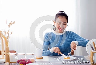 Pretty female hold spoon and knife eat food in kitchen. Stock Photo