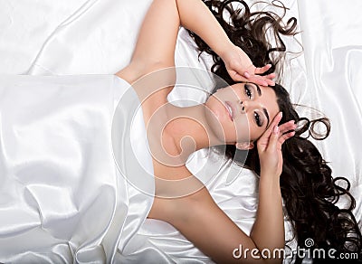 Pretty female in peignoir sleeping on bed under silk sheets Stock Photo
