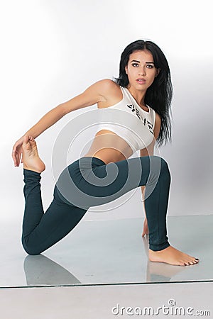 A pretty girl brunette stretching instructor, yoga, trainer, danser, posing in the studio on a white background in lasins and T- Stock Photo