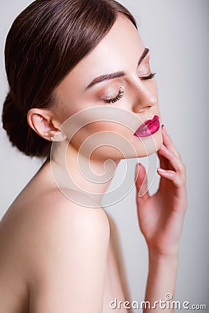 Pretty girl with closed eyes and dark hairs, with clean skin, with naked shoulders. A model with make-up and pink lips. Stock Photo