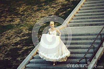 Pretty girl or cute bride walking down grey stairs Stock Photo