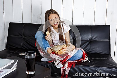 Pretty girl laughing, watching tv, sitting on sofa at home. Stock Photo