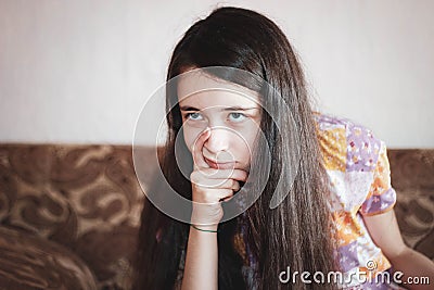 A pretty girl looks angrily at the side, holding her chin. Emotions in transition Stock Photo