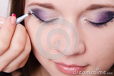 Pretty girl makeup artist draws arrows on eyes Stock Photo