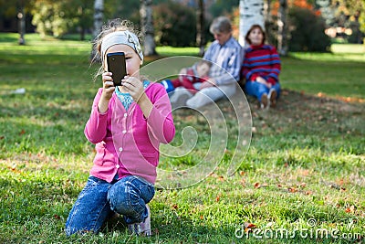 Pretty girl making picture with phone, father, mother anb brother are on background Stock Photo
