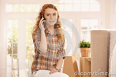 Pretty girl moved to new home smiling using mobile Stock Photo