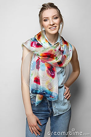 Pretty girl in jeans and colorful silk scarf posing on white background Stock Photo