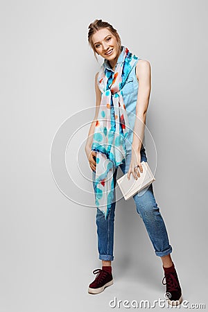 Pretty girl in rolled up jeans, gumshoes and silk scarf with book in hand Stock Photo