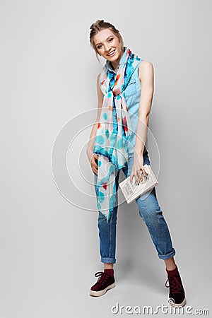 Pretty girl in rolled up jeans, gumshoes and silk scarf posing on white background Stock Photo