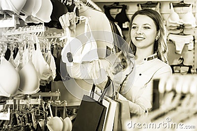 Pretty girl shopper examining bras in shop Stock Photo